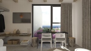 A modern living room with a large window, a dining area with two chairs, a coffee table, and a bookshelf. - Aelia Suites Milos (Milos)