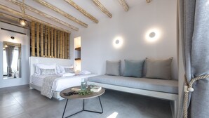 A modern bedroom with a bed, bedside table, and a sofa. - Aelia Suites Milos (Milos)