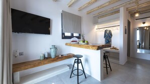 A modern kitchen with a wooden countertop, a black stool, and a hanging light fixture. - Aelia Suites Milos (Milos)