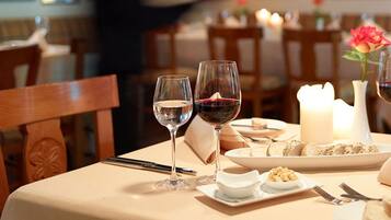 Une table à manger dressée avec des verres à vin, une bougie et une assiette de nourriture.