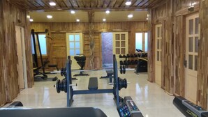 Une salle de sport avec des murs en bois, un banc de musculation et divers appareils d’exercice.