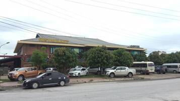 Restaurante com café no andar superior, carros estacionados e um ônibus ao fundo.