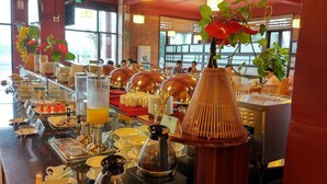 Un buffet proposant une variété de plats et de boissons, notamment une machine à café et un distributeur de jus.