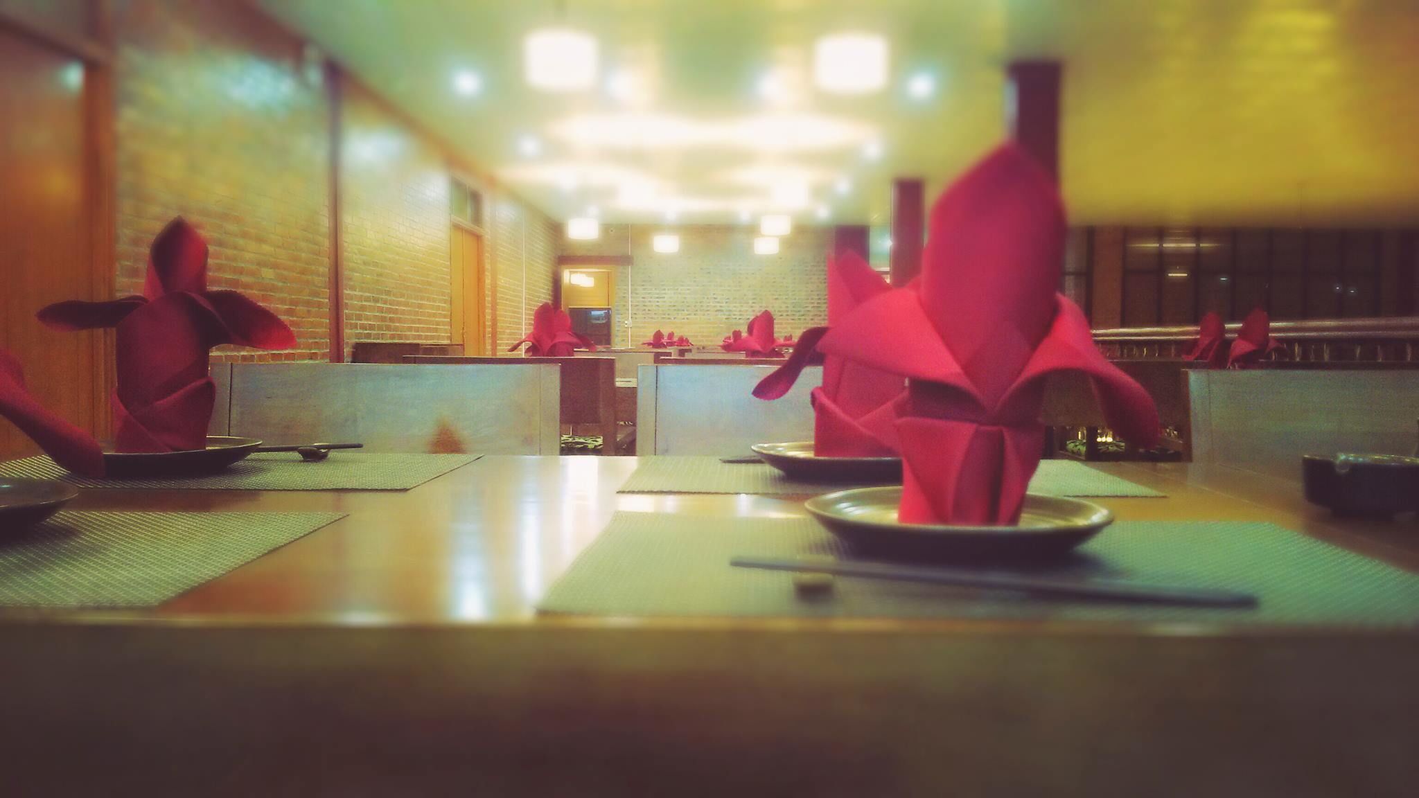 Un interior de restaurante con mesas dispuestas para comer, una zona de barra y una pared de ladrillo.