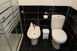 Un baño con bidé, inodoro y cabina de ducha de cristal.