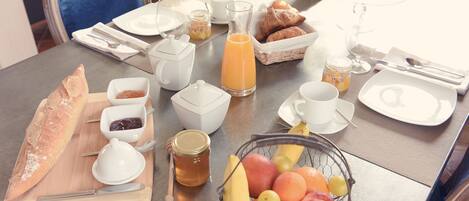 A breakfast table set with croissants, fruit, honey, and coffee.