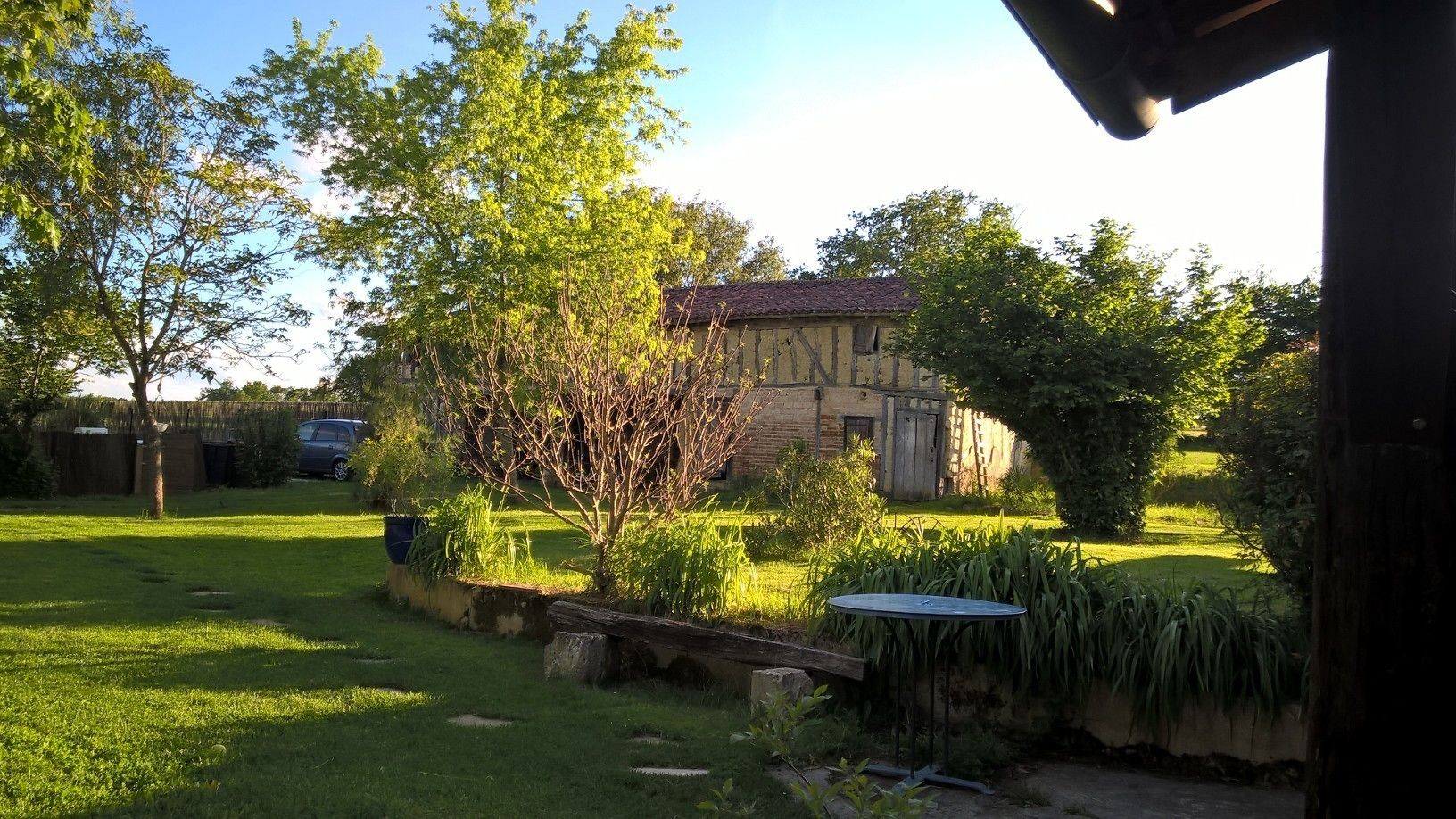 A garden with a small pond, a wooden bridge, and a building with a tiled roof.