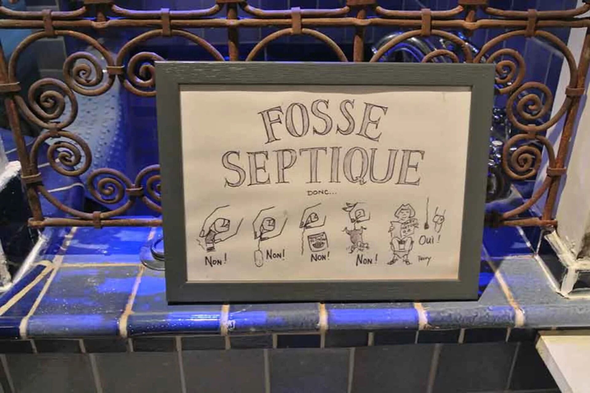 Un cartel enmarcado con el texto 'FOSSE SEPTIQUE' e ilustraciones de una mano, un rostro y una figura con un bocadillo de diálogo que dice '¡SÍ!'.
