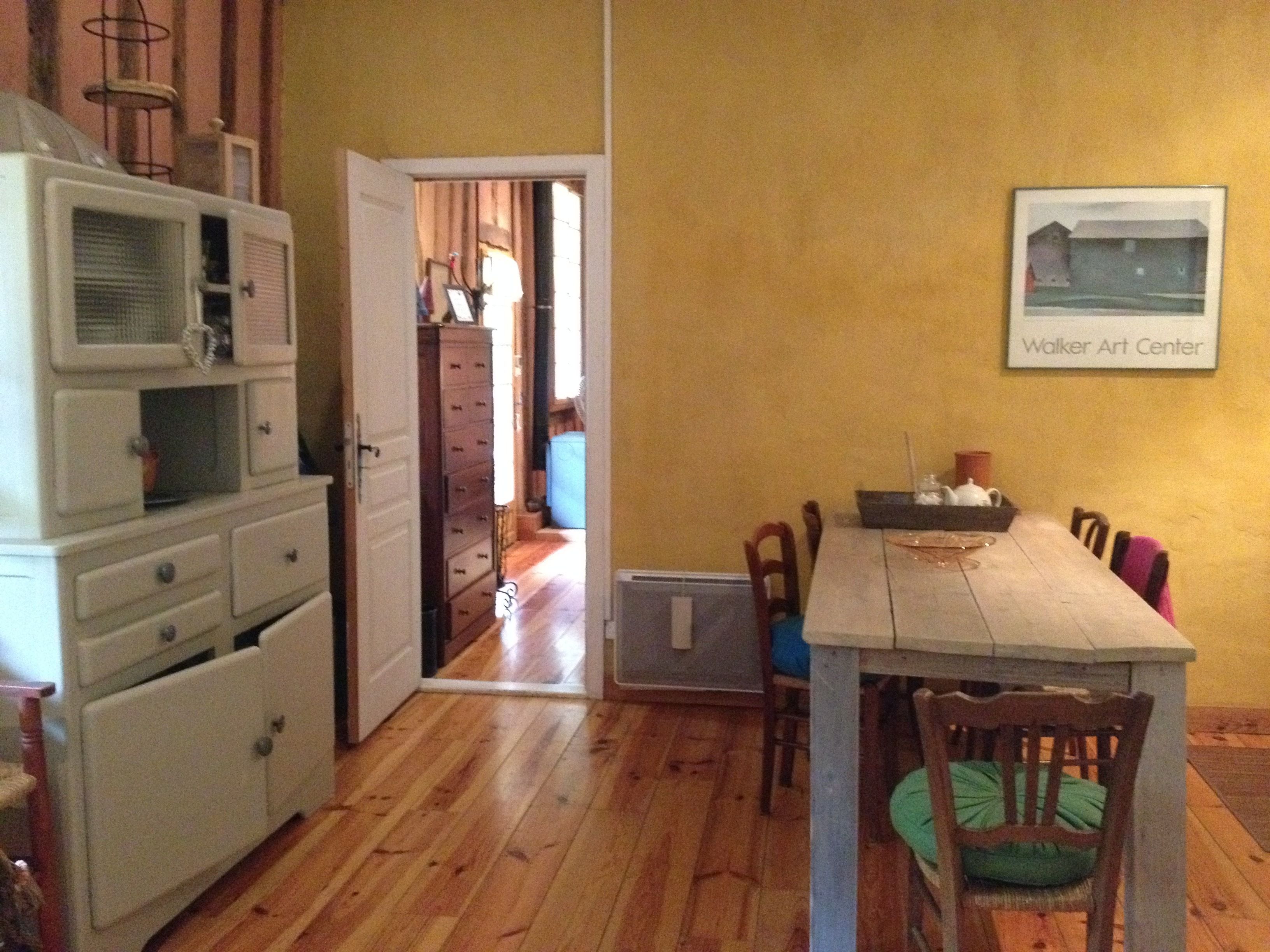 A dining area with a wooden table and chairs, a microwave, and a dresser.