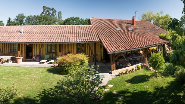 Een tweelaags huis met een pannendak, een overdekte patio met tuinmeubilair en een verzorgd gazon.