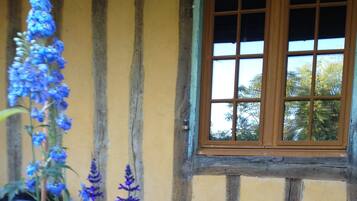 A rustic building with a yellow exterior, a wooden window, and a stack of firewood.