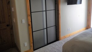 Een slaapkamer met een schuifdeurkast, een wandgemonteerde flatscreen televisie en een vloerbedekking.