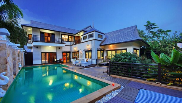 Et moderne hus med to etager, swimmingpool, udendørs møbler og en velplejet have.