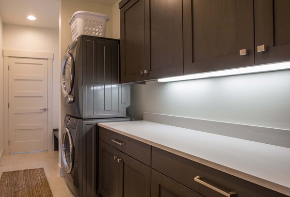 A laundry area with a washing machine, dryer, and cabinets.