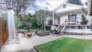Ein Haus mit überdachter Terrasse, kleinem Garten und einer Treppe zu einer Holzterrasse.