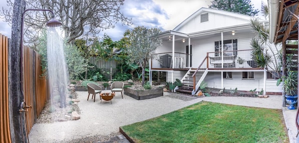 Une maison dotée d’un patio couvert, d’un petit jardin et d’un escalier menant à une terrasse.