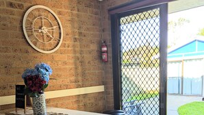 A room with a white table, a decorative clock, and a vase with flowers. - 3 Min walk to the beach,  this little slice of heaven is your perfect getaway! (Culburra Beach)