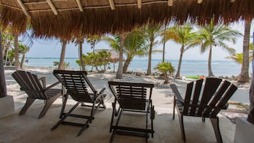 Relax in comfort with ocean views from Adirondack chairs under a shaded thatched roof.