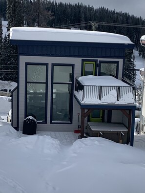 A modern house with a balcony, large windows, and a snow-covered roof.