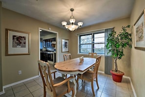 A dining area with a wooden table and chairs, a chandelier, a potted plant, and framed artwork on the walls.