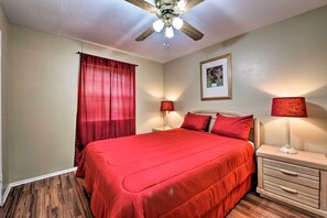 A bedroom with a large bed, two bedside tables with lamps, a ceiling fan, and a framed picture on the wall.