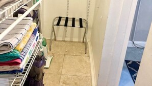 Une petite salle de bain avec des étagères où sont rangées les serviettes et les articles de toilette.