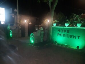 A nighttime view of a residential area with a sign reading "HOPE RESIDENT" and illuminated green lights. - Hope Residence (Anuradhapura)