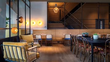 A modern dining area with a long table, multiple chairs, and a staircase in the background.