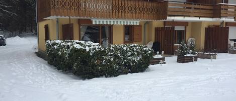 Un bâtiment à deux étages doté d’un balcon, d’un jardin recouvert de neige et d’une voiture garée.