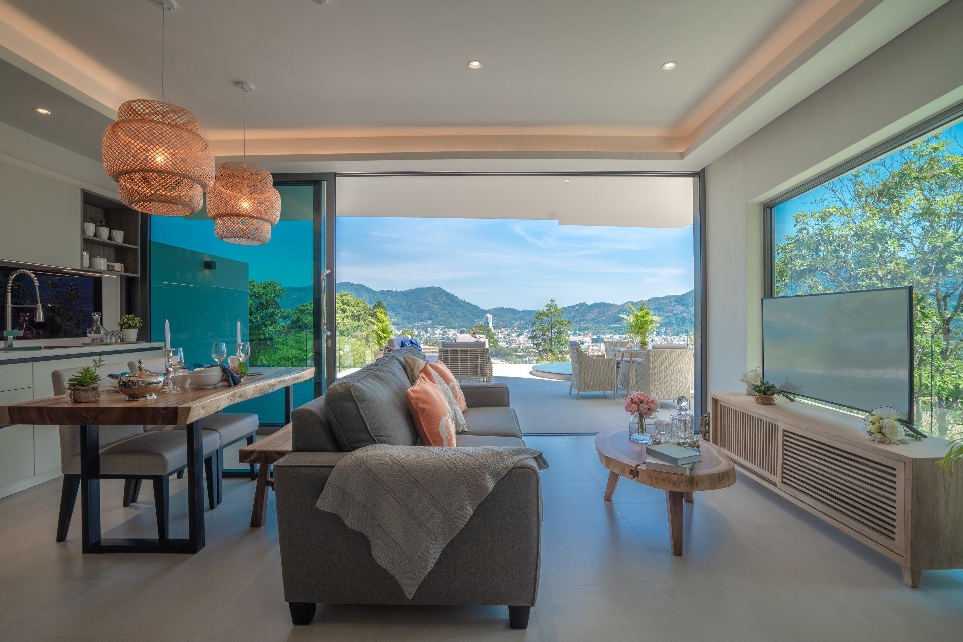 Una sala de estar moderna con un sofá, una mesa de comedor y vistas a un paisaje urbano a través de amplios ventanales.