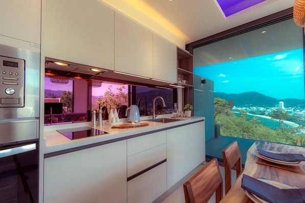 Una cocina moderna con un ventanal amplio que ofrece vistas a la ciudad, un horno empotrado y un comedor con mesa y sillas.