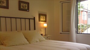 Een net opgemaakt bed met een hoofdbord, een bedlampje en lijstjes met kunst aan de muur.