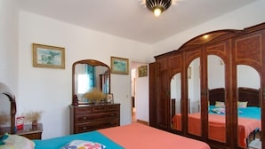 Ein Schlafzimmer mit einem Bett, einem Schminktisch, einem Kleiderschrank und zwei gerahmten Bildern an der Wand.