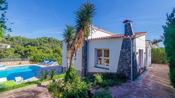 Eine Villa mit Swimmingpool, Steinhausfassade und Blick auf die grüne Umgebung.