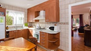 Eine kompakte Küche mit Holzausstattung, einem Gasherd, einer Mikrowelle und einem Essbereich mit Tisch und Stühlen.