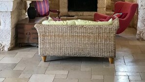 A cozy room with a stone archway, a fireplace, a wicker sofa, and two red chairs. - Idyllic olive mill with heated pool, in an olive grove, close to sea and Ostuni (Ostuni)