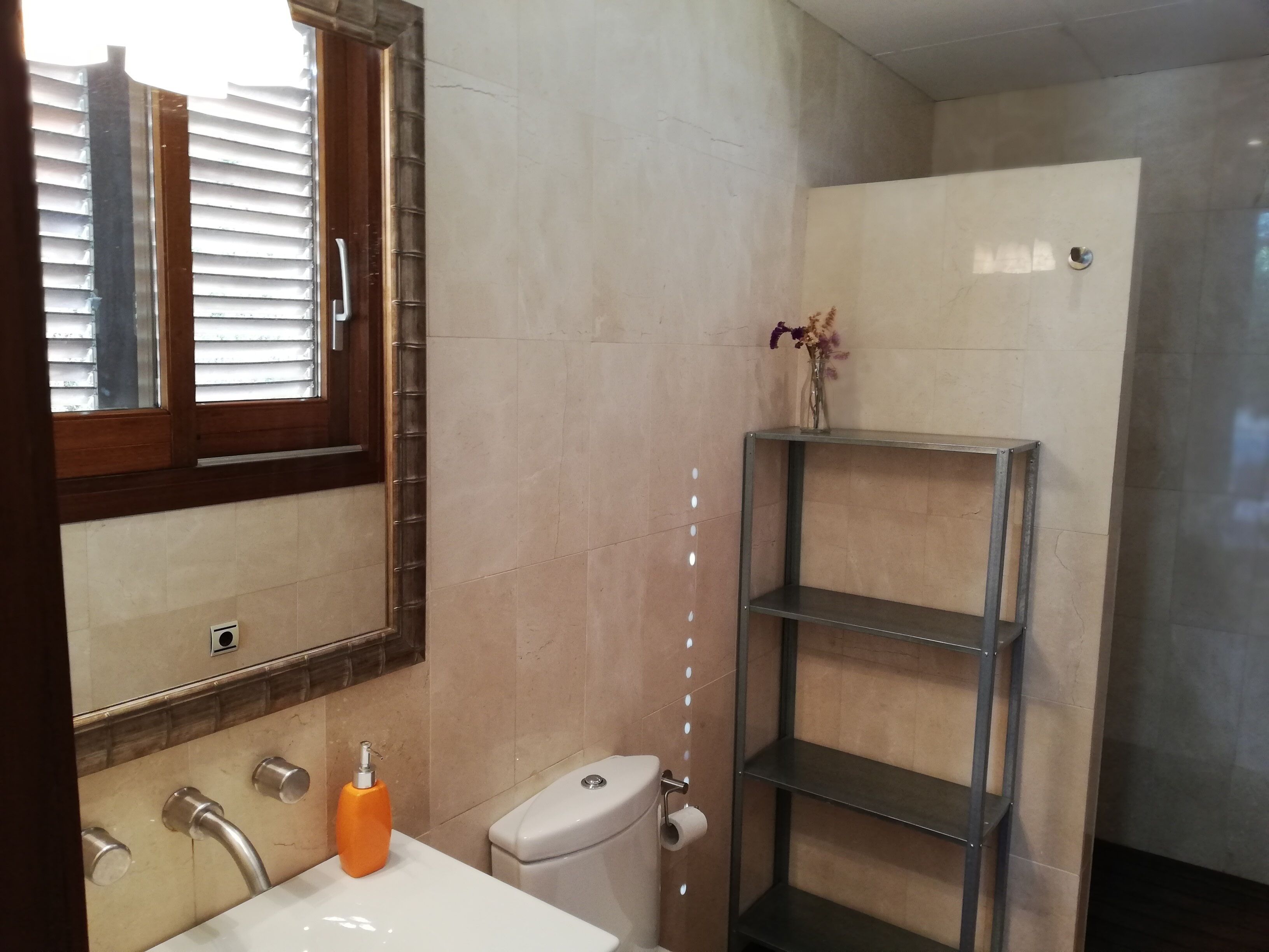 Une salle de bain équipée de toilettes, d’un lavabo, d’un miroir et d’une étagère.