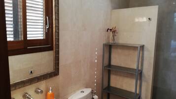 Une salle de bain équipée de toilettes, d’un lavabo, d’un miroir et d’une étagère.