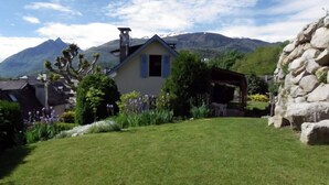 Una casa con tetto spiovente, un camino e un piccolo portico con tavolo e sedie.