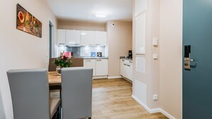 Una cocina moderna con armarios blancos, una mesa de comedor con sillas y un cuadro decorativo en la pared.