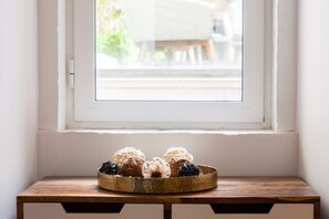 A wooden table with a brass tray holding decorative items by a window.