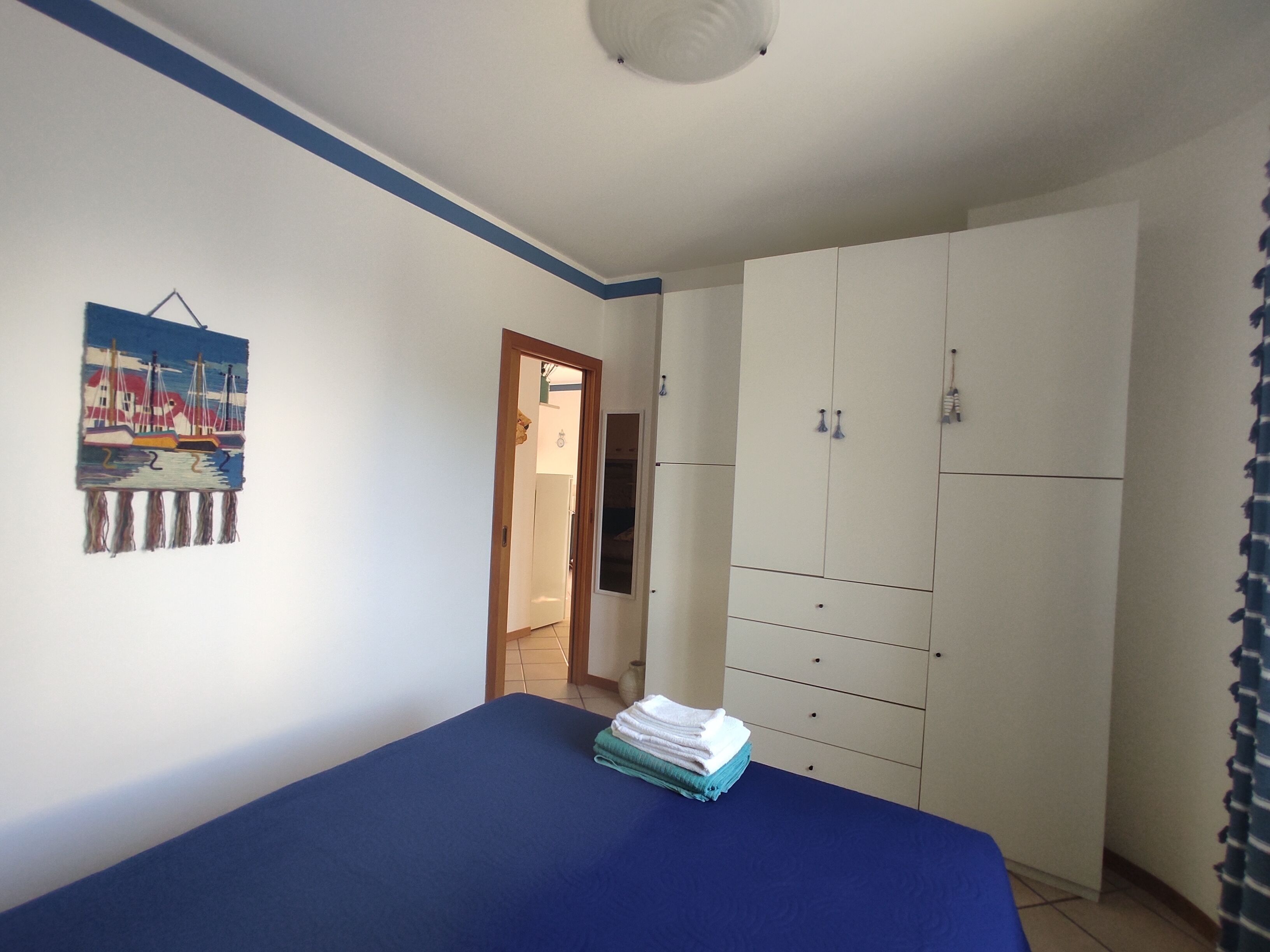 A bedroom with a bed, a wardrobe, and a painting on the wall.