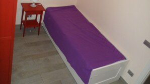 A small room with a bed, a nightstand, and a red wardrobe.