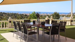 Un patio al aire libre con una mesa y sillas, con vistas a un paisaje urbano y al mar.