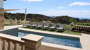 Zona de piscina con sillones de descanso y vistas al paisaje.