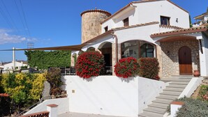 Un edificio blanco con una torre de piedra, flores rojas y una escalera que lleva a la entrada.