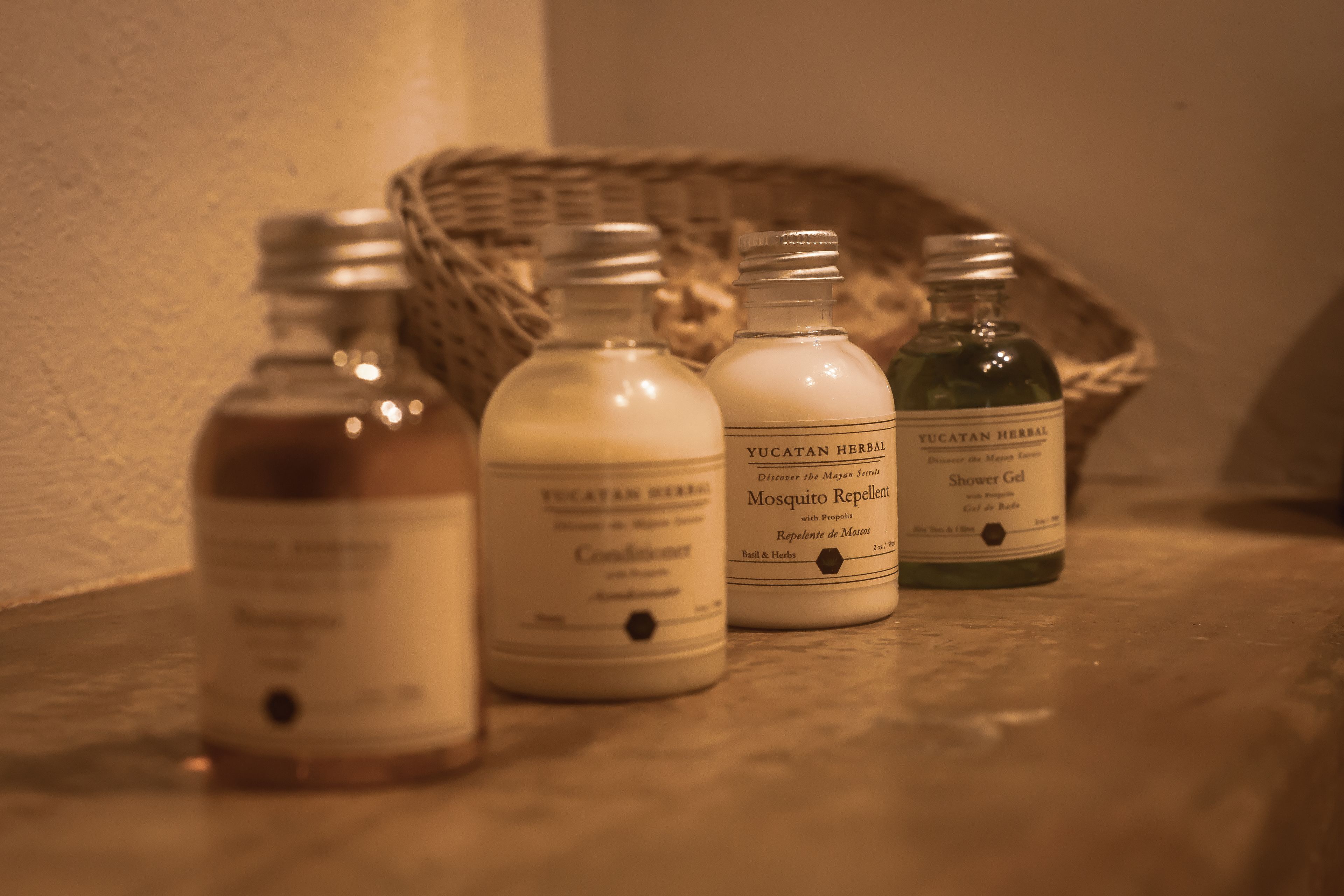 Four bottles of Yucatan herbal products on a wooden surface.