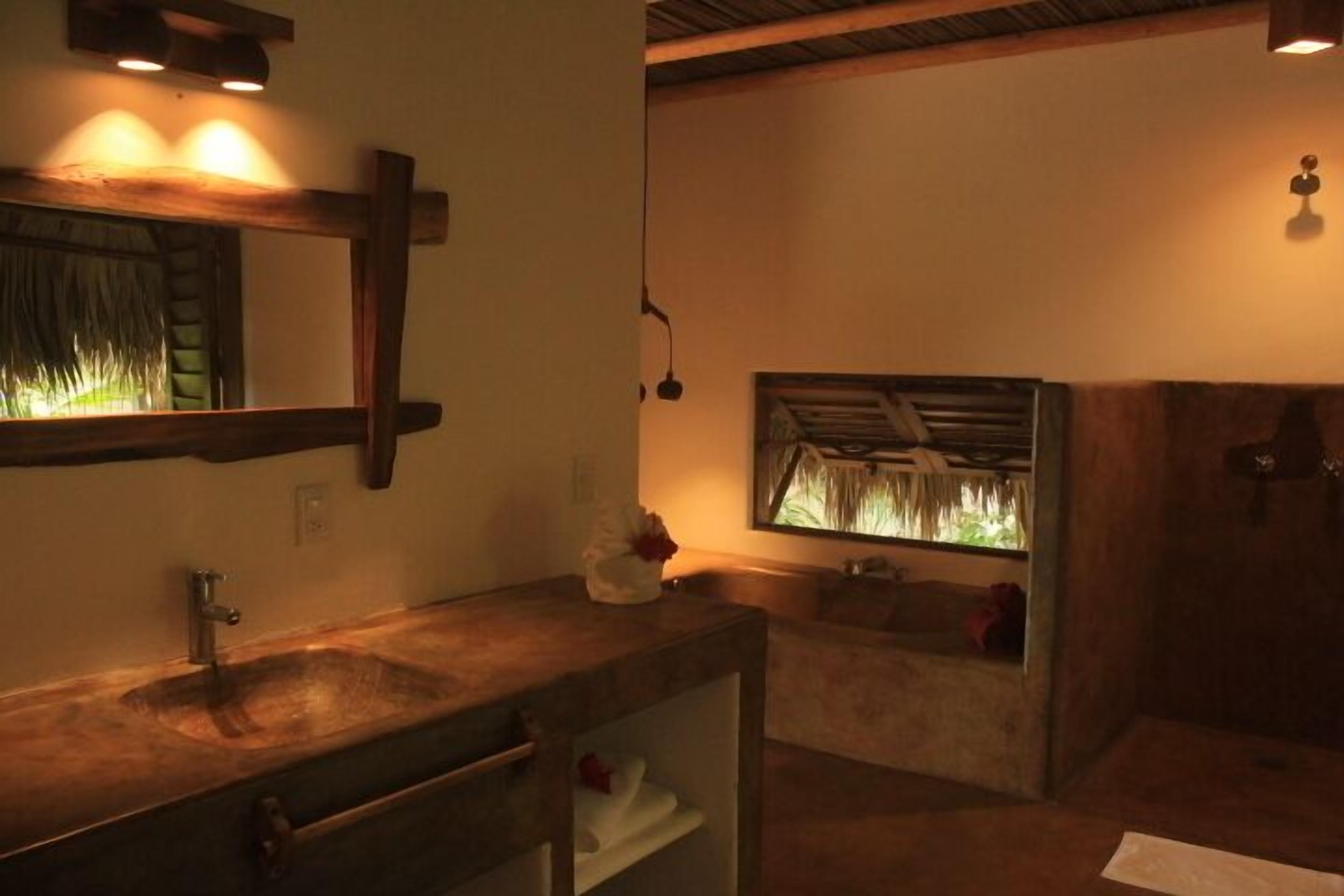 Un baño con tocador de madera, un espejo grande y zona de ducha.
