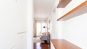A modern interior with a wooden floor, white walls, a grey sofa, and a black floor lamp.
