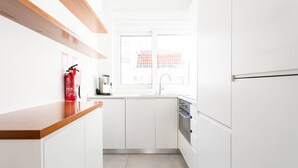 A modern kitchen with white cabinets, a wooden countertop, a stainless steel range hood, and a window with a view of traditional architecture.